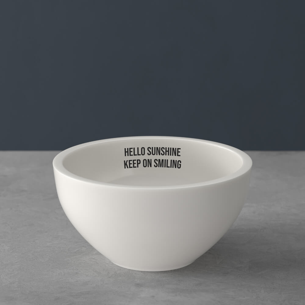 Eine weiße Schale auf einer grauen Oberfläche mit der Aufschrift "HELLO SUNSHINE KEEP ON SMILING".