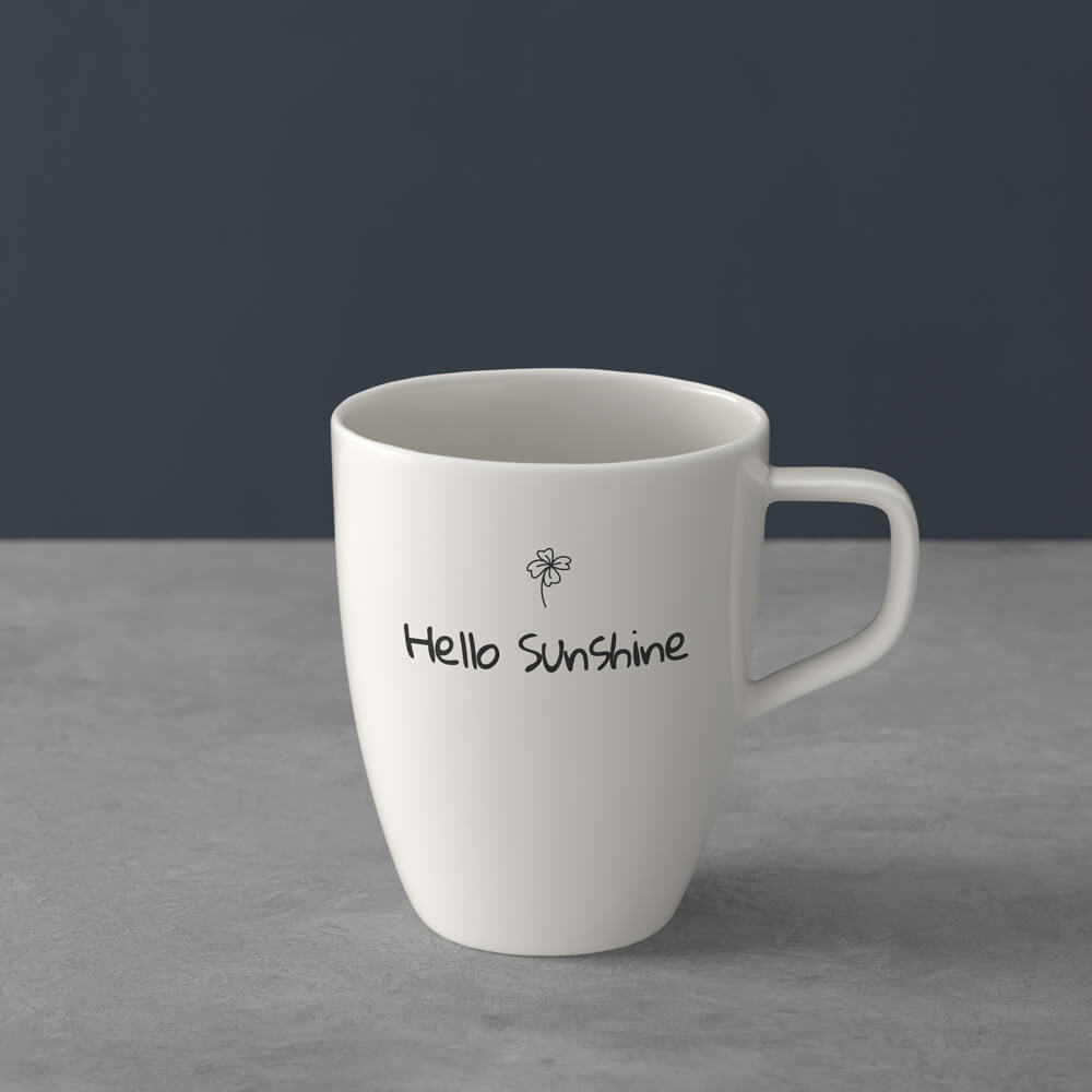 1041309651_gloria-hallelujah_schwarz_icon Weißer Keramikbecher mit dem Aufdruck "Hello Sunshine" und einer kleinen Sonnenillustration auf der Vorderseite, platziert auf einer grauen Oberfläche.