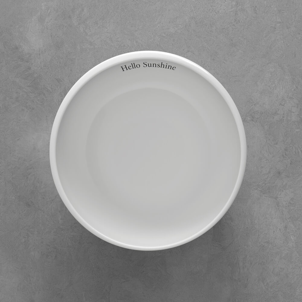 1042641900_VilleroyundBoch_schwarz Eine weiße Schale auf grauer Oberfläche mit der Aufschrift "Hello Sunshine" am inneren Rand.