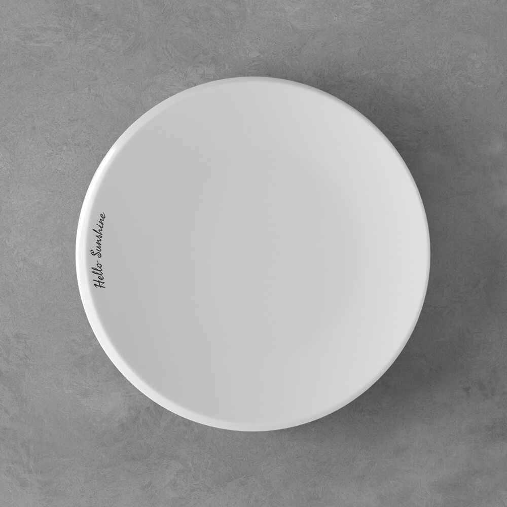 Ein schlichter, weißer, runder Teller mit dem Schriftzug "Hello Sunshine" am Rand, der auf einer grauen Fläche steht.